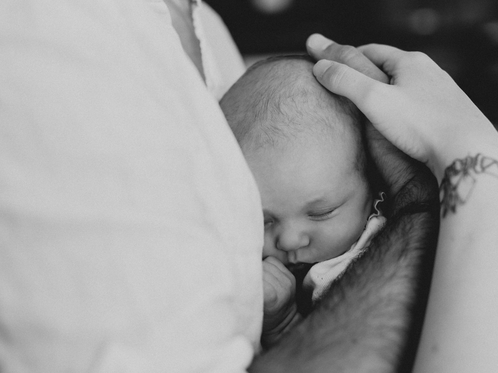 Photo de bébé breton dans les bras capté par un photographe de naissance en bretagne