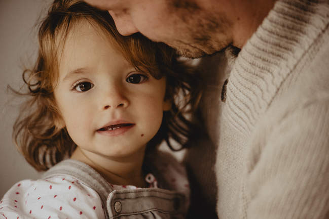 portrait d'une petite fille dans les bras de papa devant le photographe de naissance