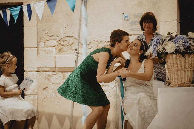 la témoin embrasse la mariée devant l'objectif du photographe
