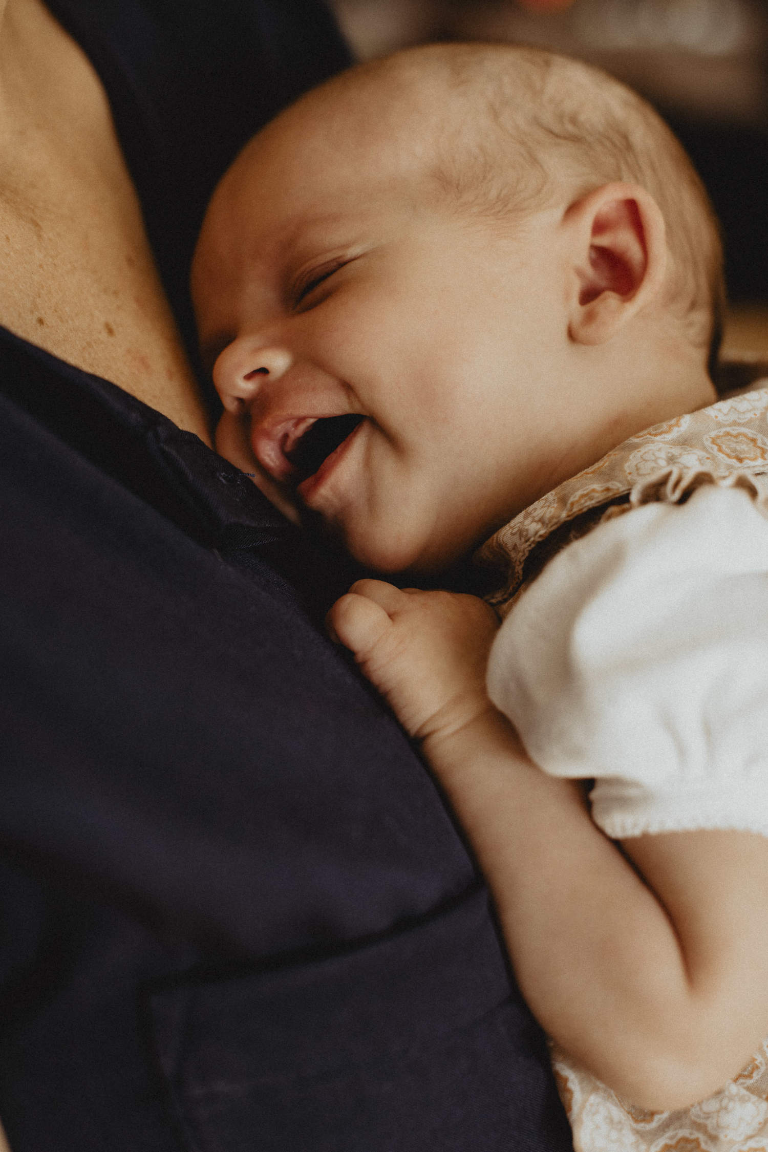 Photographe de maternité captant le sourire d'un bébé dans les bras de sa maman